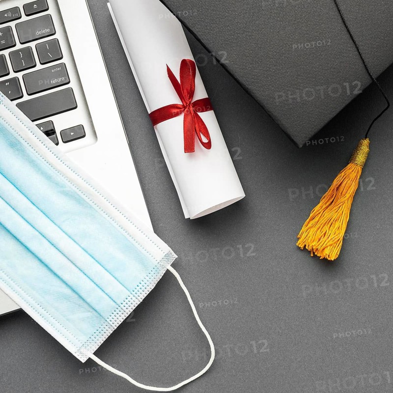 Top view laptop with medical mask academic cap