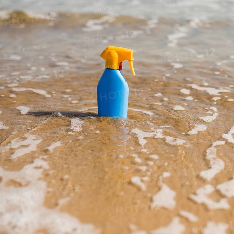 Blue sunscreen plastic bottle shallow sea water beach