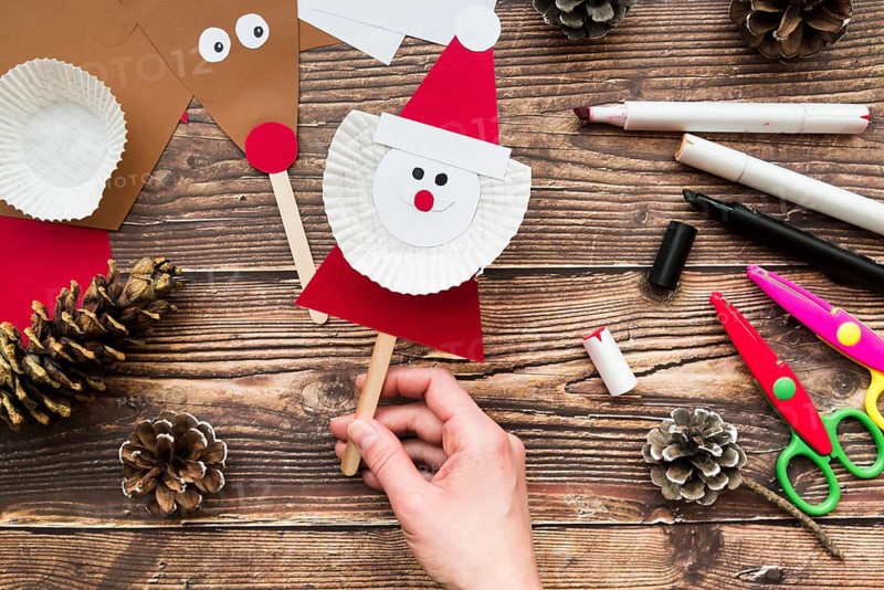 Elevated view woman s hand holding santa claus prop table