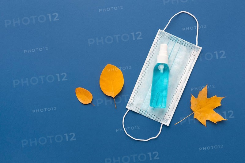 Flat lay medical mask with hand sanitizer autumn leaves