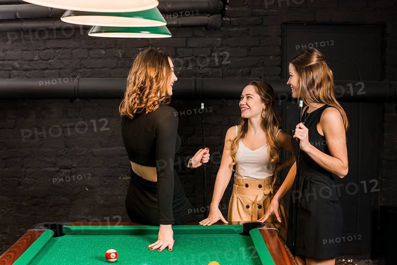 Group happy female friends standing near snooker table