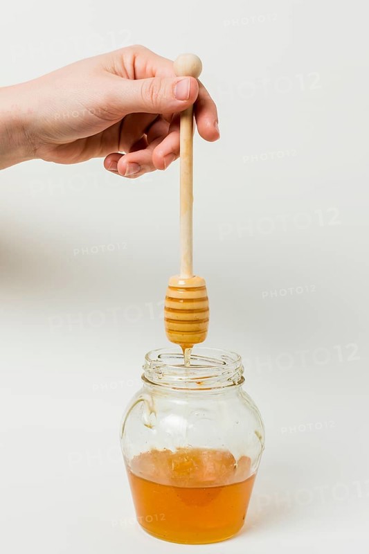 Hand holding honey spoon