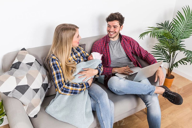 Happy parents with sleeping baby using laptop