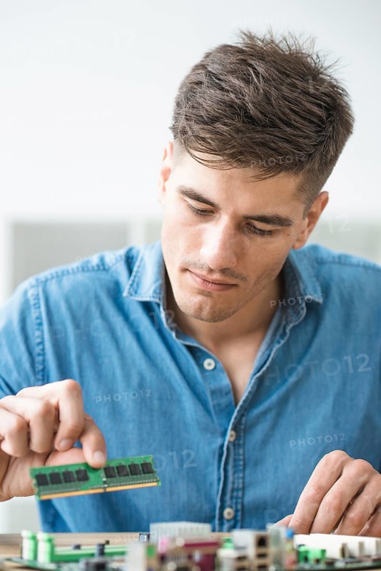 Male technician installing ram computer motherboard