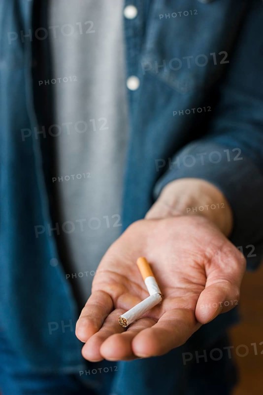 Man holding broken cigarette his hand