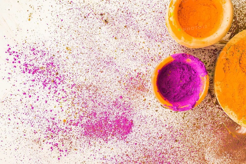 Pink yellow holi powder bowl with stained white background