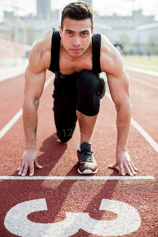 Portrait confident male athlete starting line race track