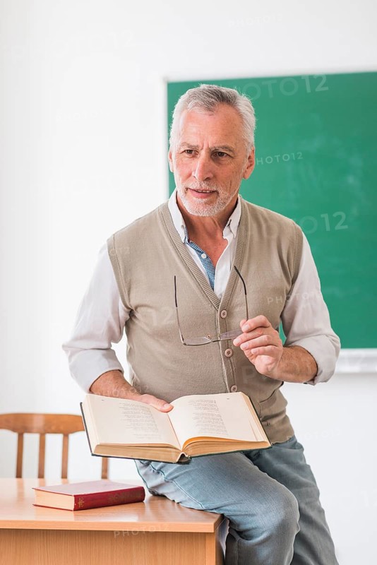 Senior professor sitting desk with book classroom