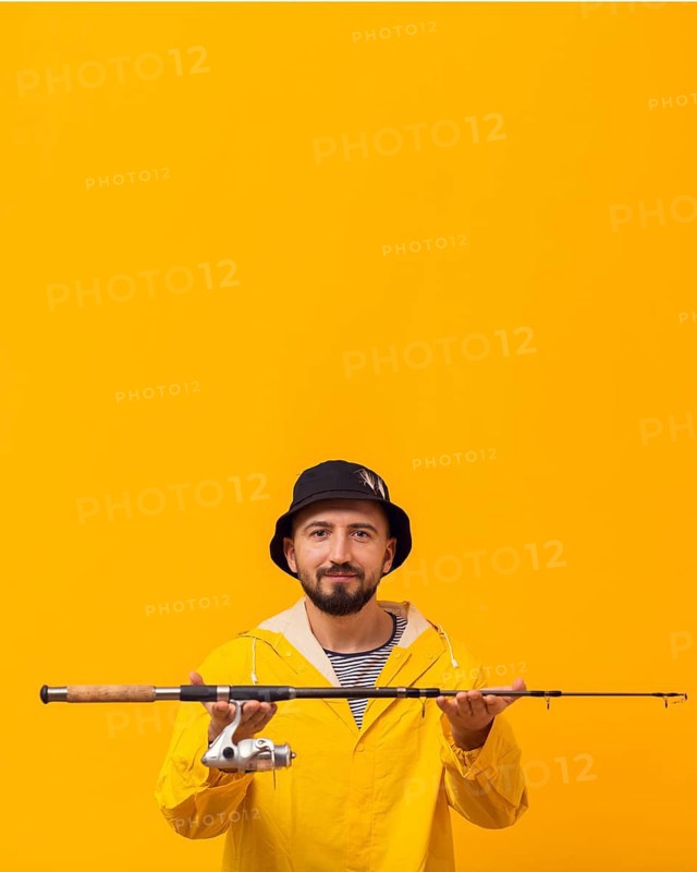 Smiley fisherman holding up fishing rod with copy space