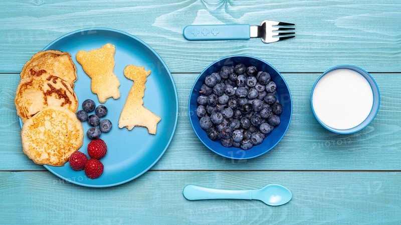 Top view blueberries with baby food cutlery