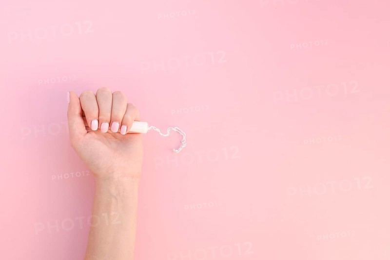 Top view hand holding tampon pink background