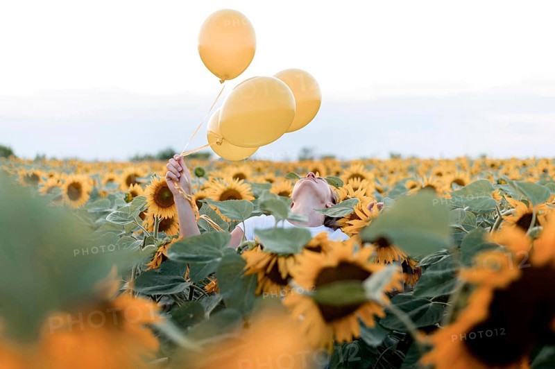 Woman holding balloons sunflower field