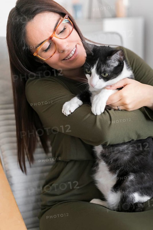 Woman playing with cat sitting chair