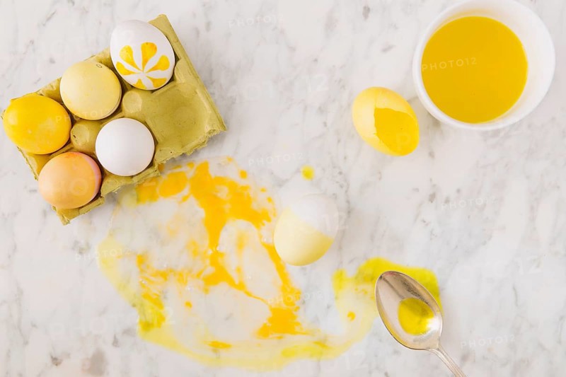 Yellow easter eggs container near spoon dye liquid