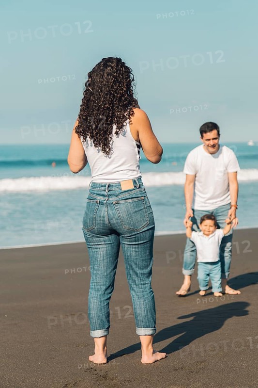 Young parents playing with baby beach