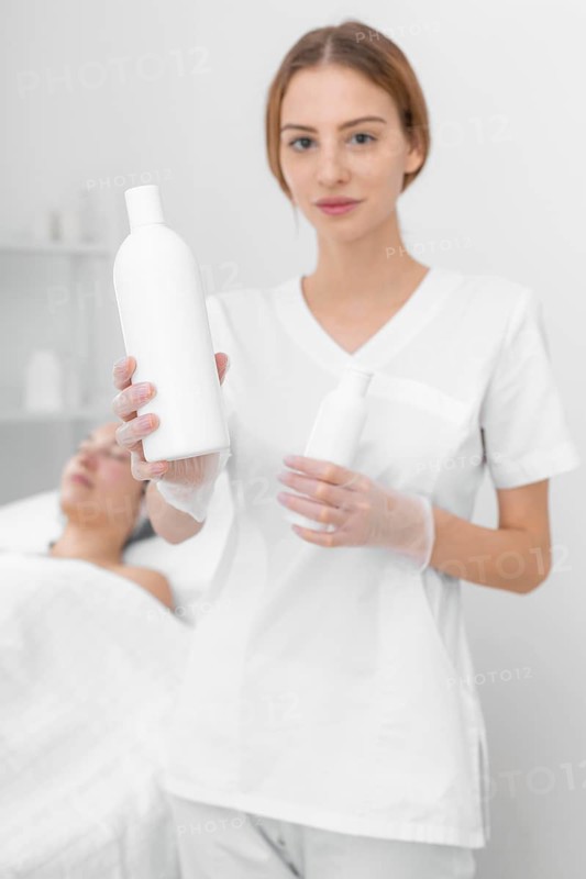 Beautician with lotion female client 2