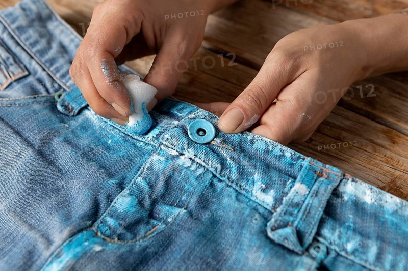 Close up hands coloring jeans with blue paint