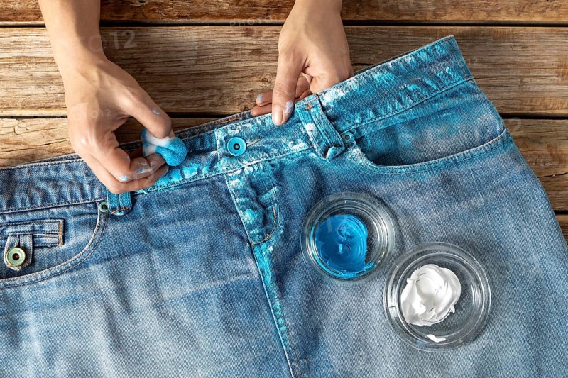 Close up hands coloring jeans with paint