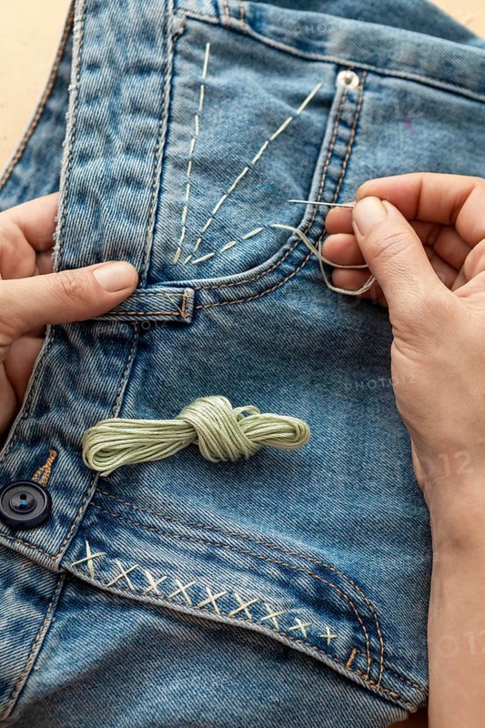Close up hand sewing jeans