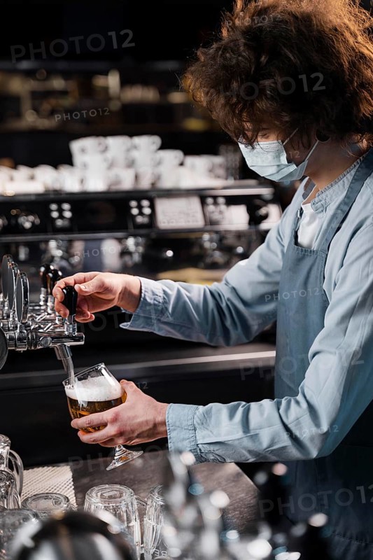 Close up man with mask pouring beer