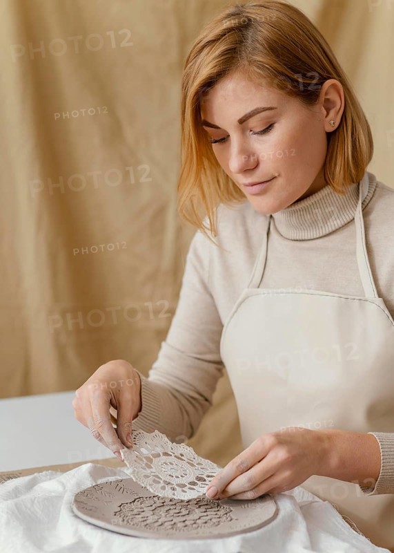 Close up woman decorating clay plate