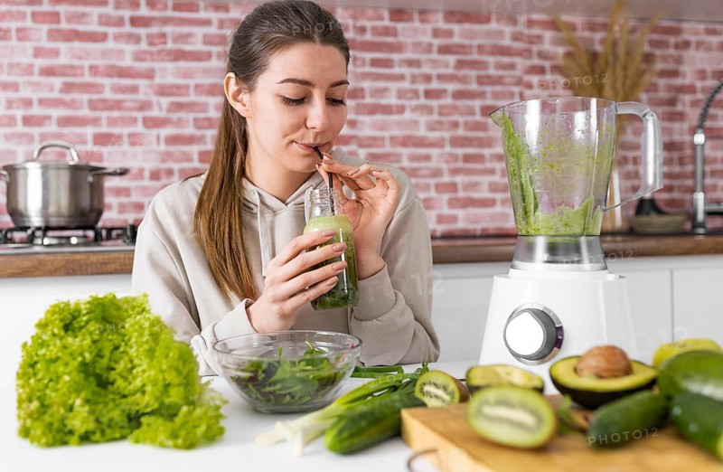 Medium shot woman drinking green smoothie