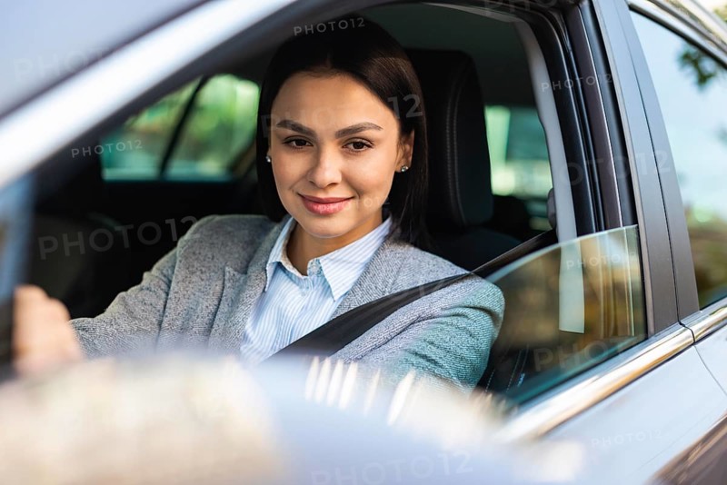 Smiley businesswoman driving her car looking side mirror