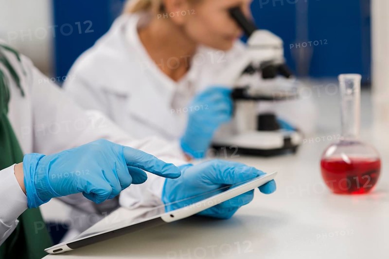Side view female scientists lab working with microscope tablet