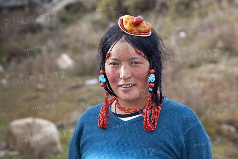 Portrait of Tibetan Khampa woman wearing traditional amber and red coral hair piece at Zhuqing