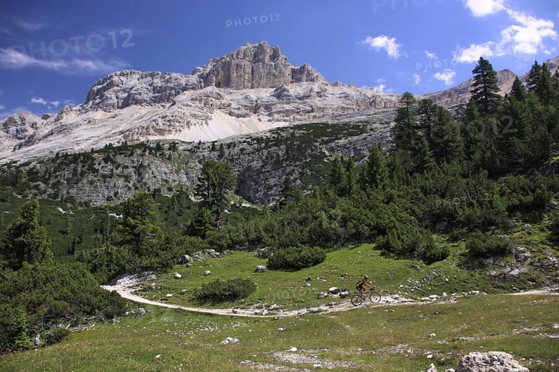 Mountain biker riding bike along path in the mountains of the Dolomites at Alta Badia