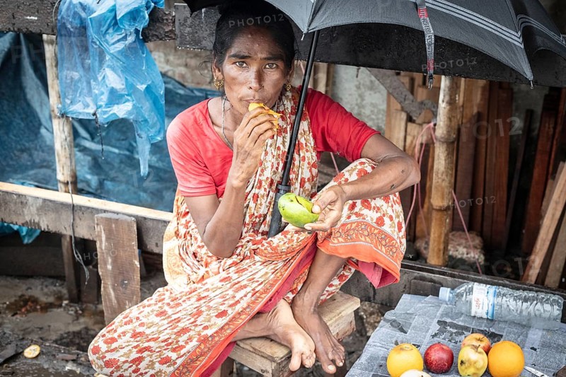 Woman eating a mango in front of her house