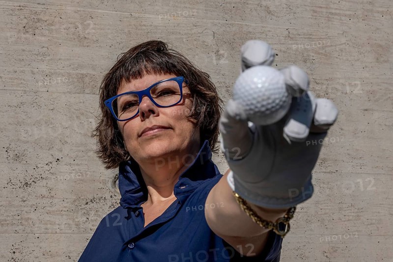 Golfer with a Glove Holding Up Her Golf Ball in a Sunny Day in Switzerland