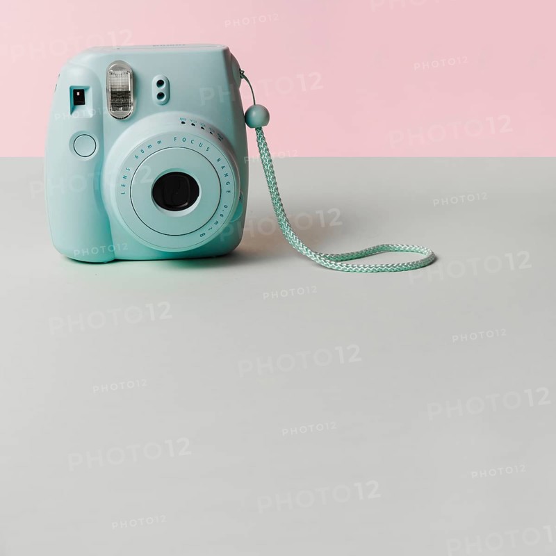 Mini blue instant camera gray desk against pink background