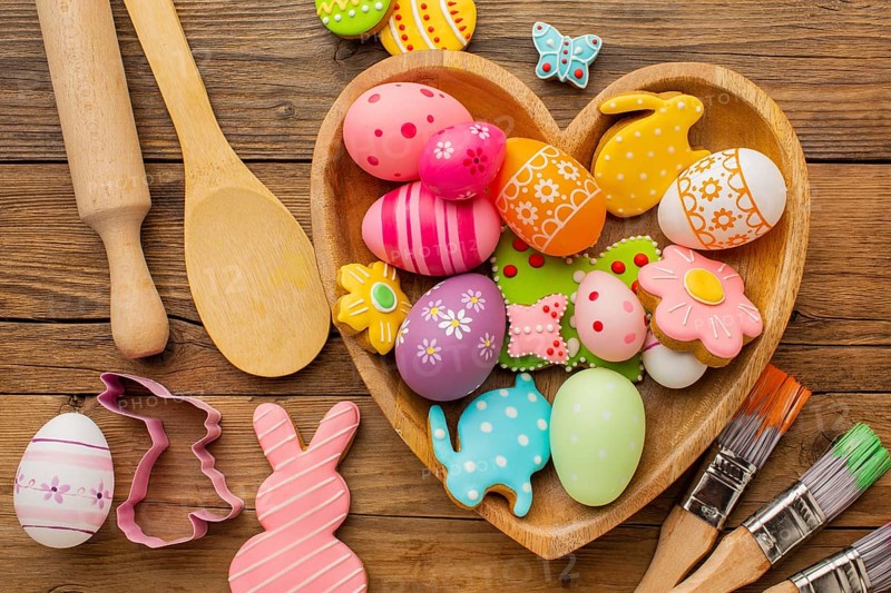 Top view colorful easter eggs heart shaped plate with kitchen utensils paint brushes