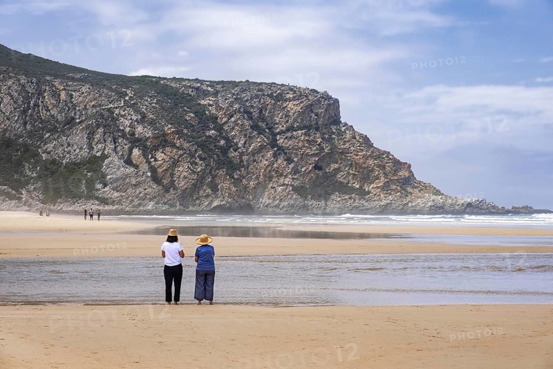 Tourists walking on Nature's Valley sandy beach in the Tsitsikamma Section of the Garden Route National Park