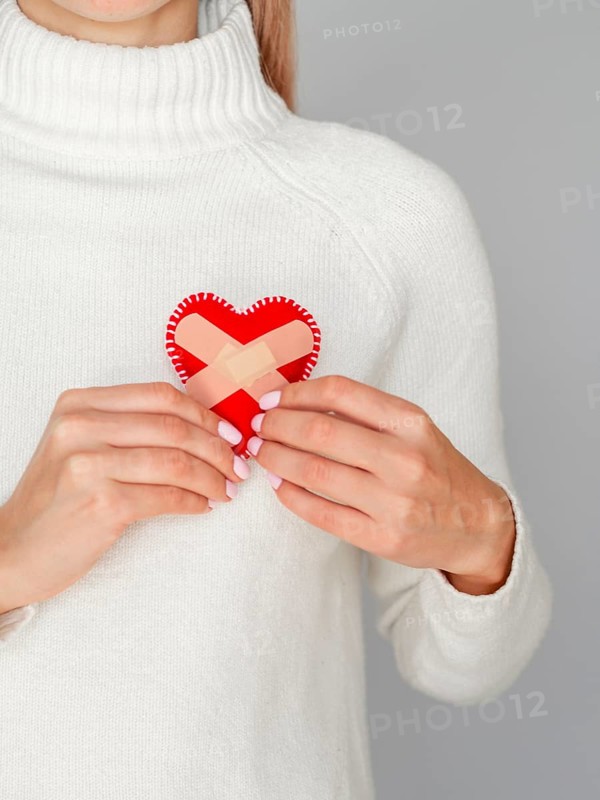 Woman holding heart with band aids