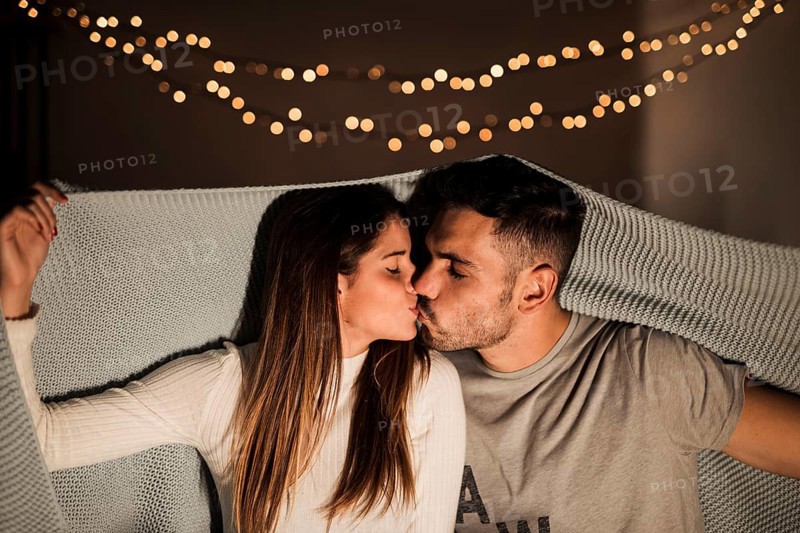 Young woman kissing with man coverlet