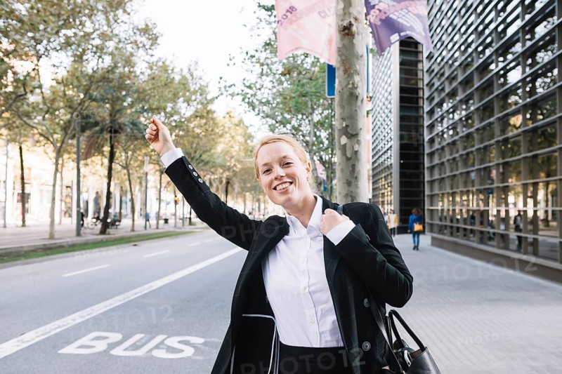 Cheerful executive formal wear catching taxi street