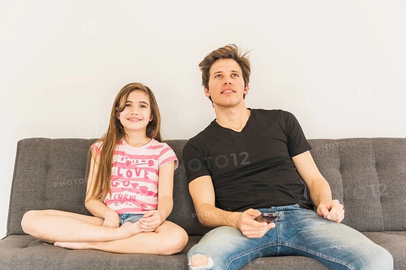 Smiling girl sitting sofa with her father