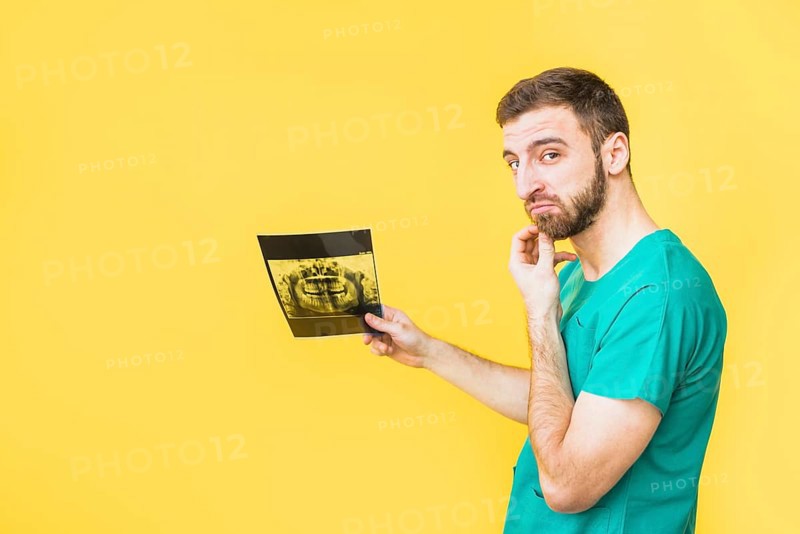 Thoughtful dentist holding teeth x ray