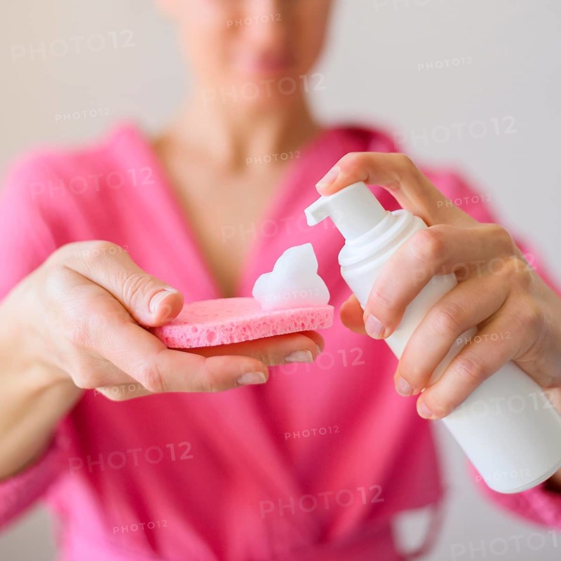 Front view woman using face cleanser