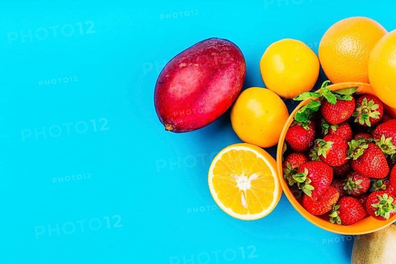 Mango oranges bowl strawberries blue background