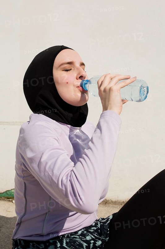 Woman with purple jacket drinking water
