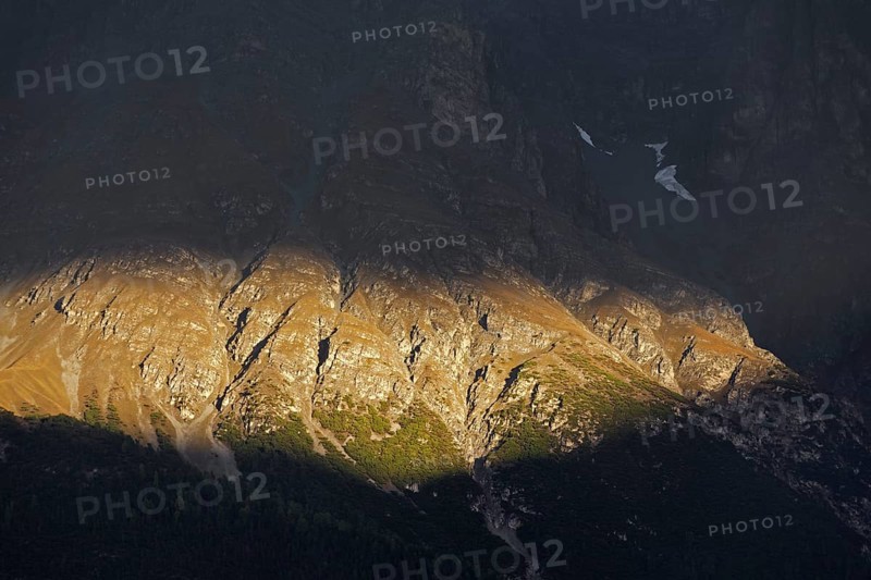 Sunlit rock face showing coniferous tree line
