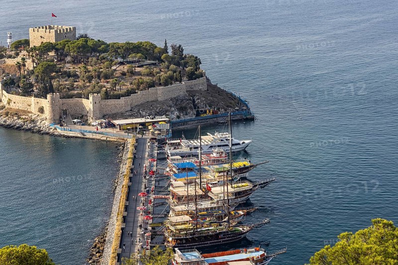 Excursion boats moored at the causeway to Pigeon Island in the bay of Kusadasi. A Genoese fortress towers on the summit of the island Kusadasi