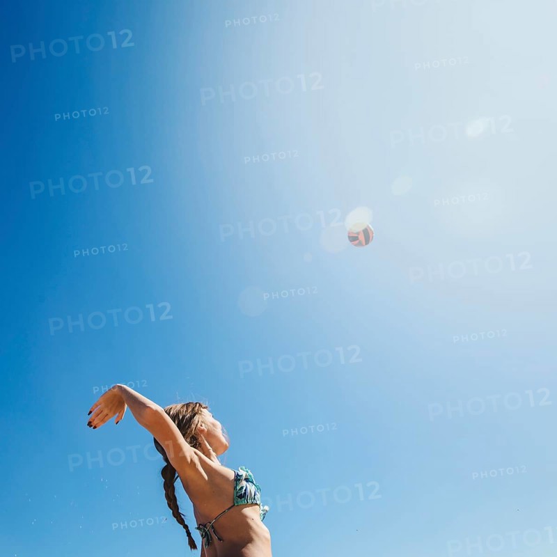 Woman playing beach volley with sun background