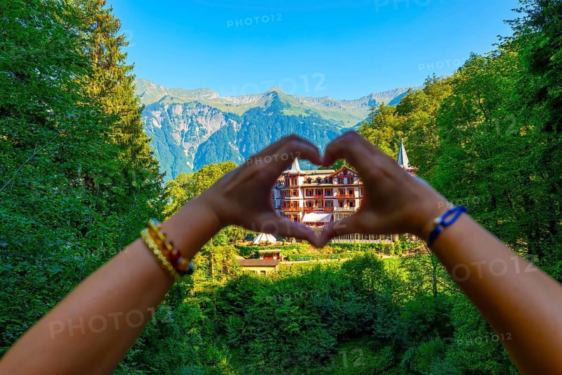 Woman Making a Heart Shape in Front of The Historical Grandhotel Giessbach on the Mountain Side in Brienz