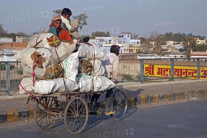 Tricycle rickshaw transporting children sitting on heavy load in Agra