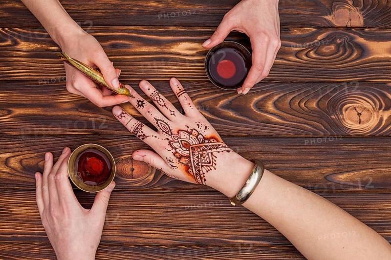 Artist making mehndi womans hand drinking tea