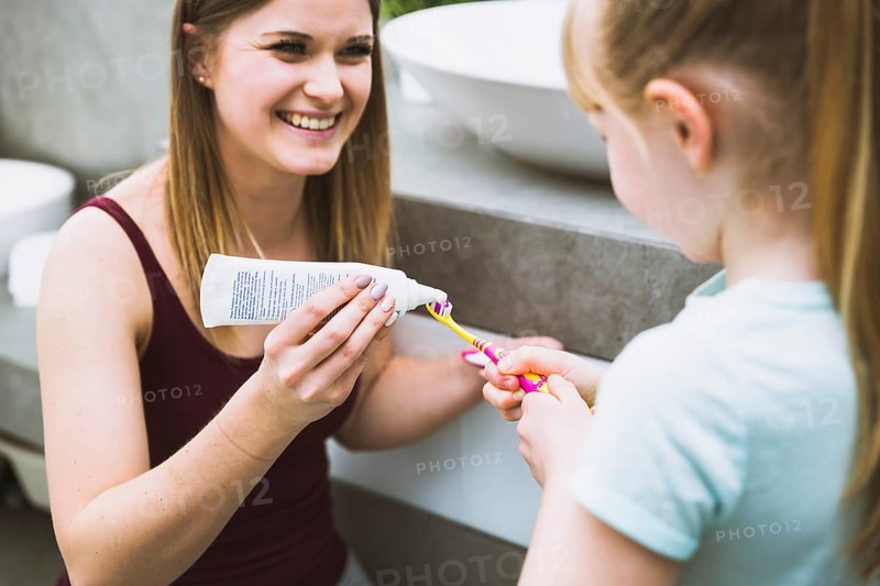 Charming woman helping daughter with toothpaste